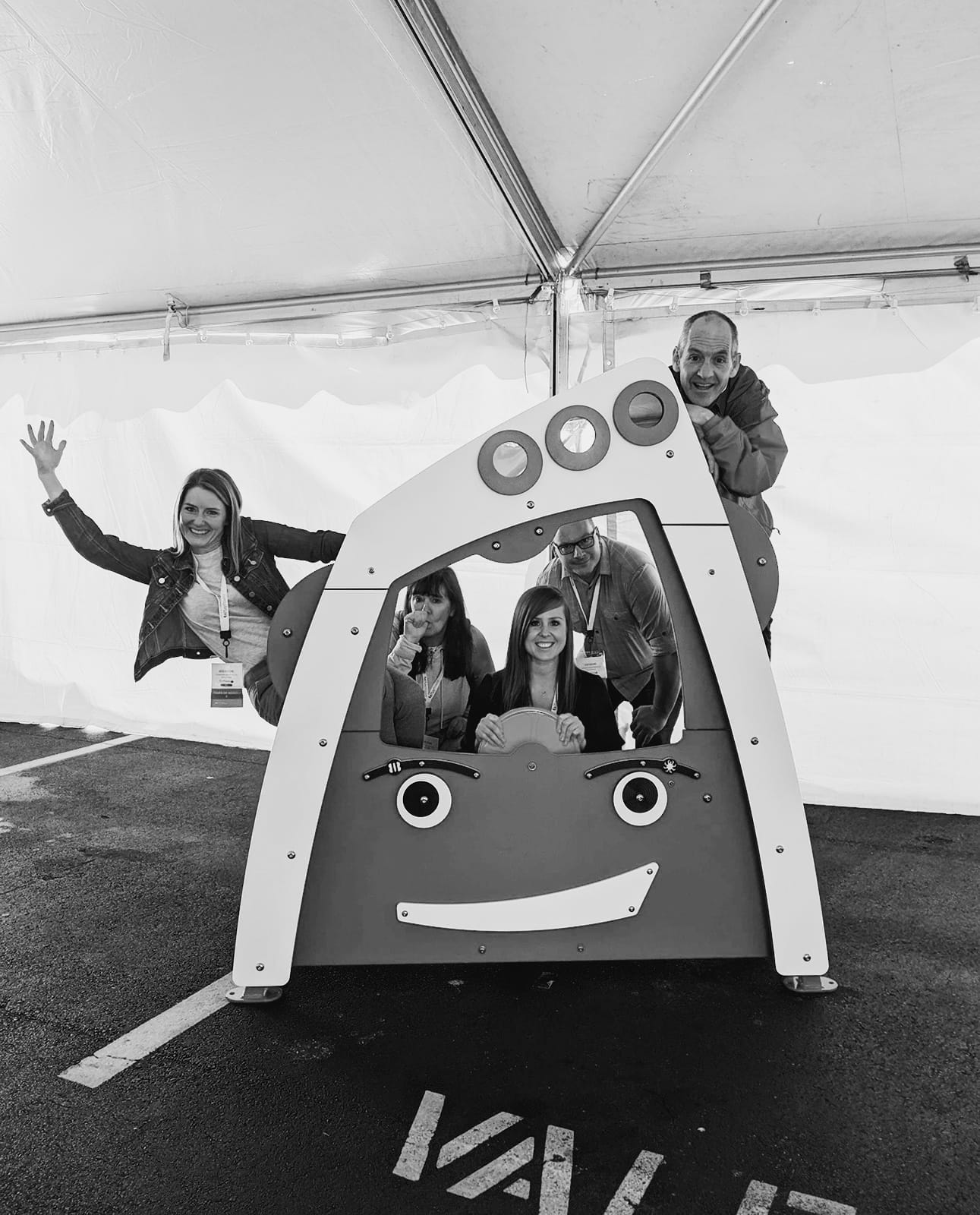 Black and white team photo of Katie Hodgins, Lori Vogelaar, Lauren Sinclair, Ken Schamp, and Robert McCoy playing on a Tot Builders Truck.