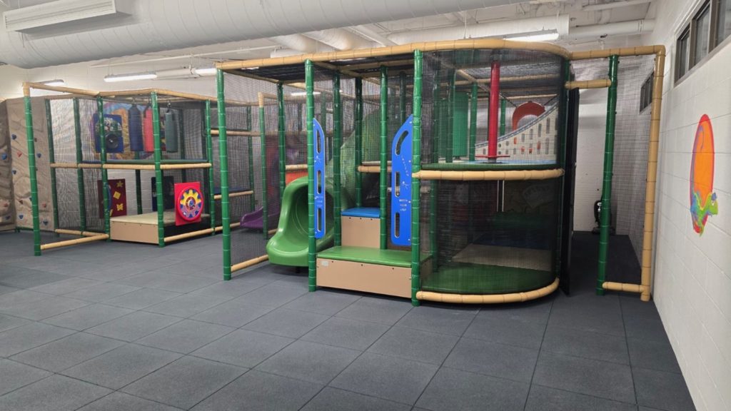 Village Square Leisure Centre-06 Indoor playground with colorful slides, climbing structures, and padded flooring. The space feels safe and inviting, designed for children's play.