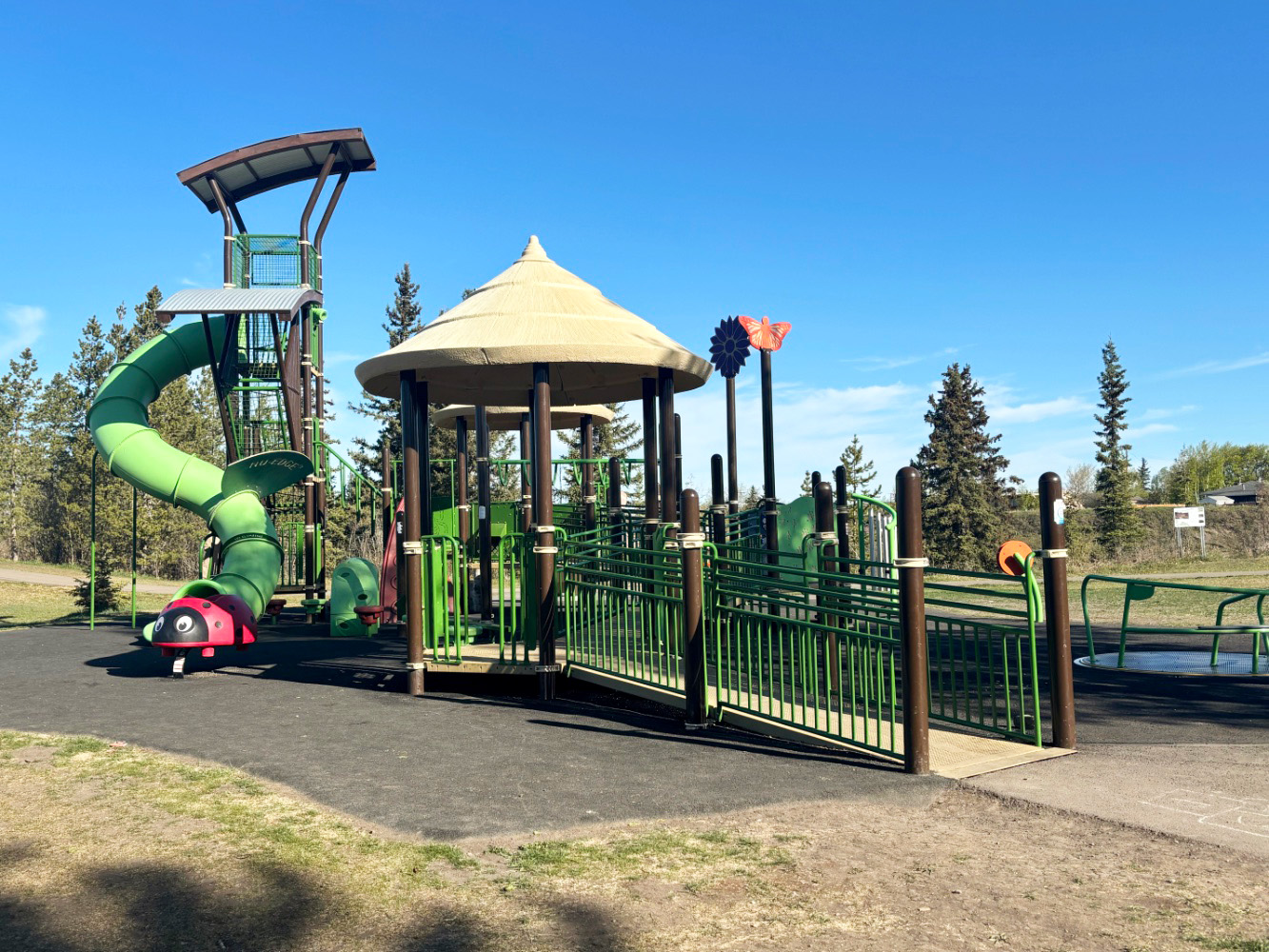 Kin Park-06 Railed ramp leading up to a gazebo deck at Kin Park in Dawson Creek, BC, with an inclusive merry-go-round nearby.