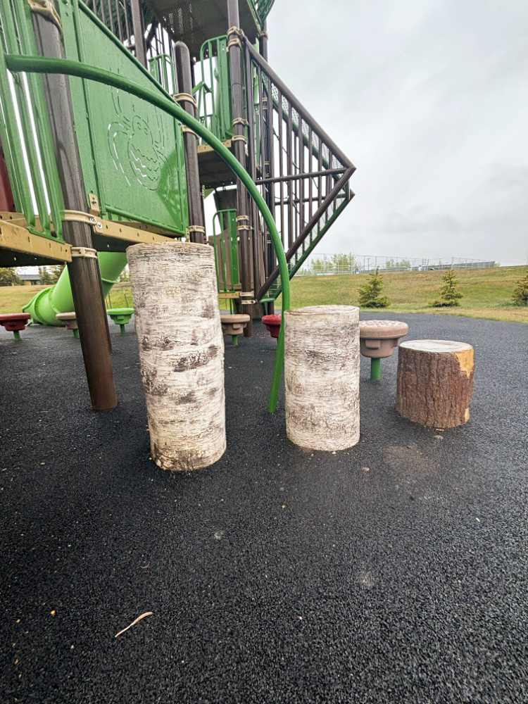 Kin Park-09 Various heights of birch log stepping stumps on black rubber surfacing at Kin Park in Dawson Creek, BC.