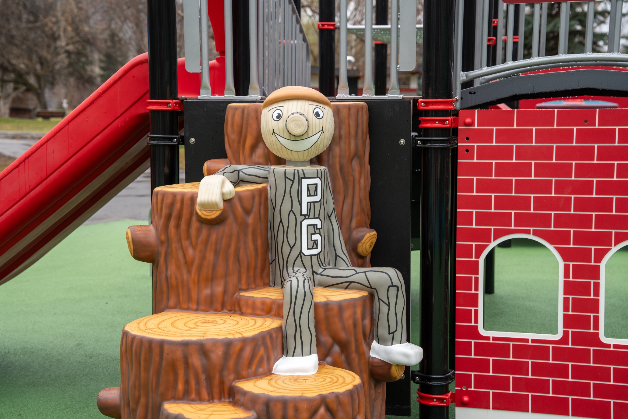 Smiling wooden log mascot named "Mr. PG", seated on tree stump climbing steps.
