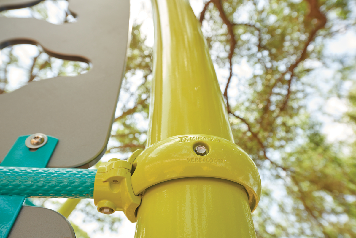 Close-up of a yellow post clamp connector, a structural detail that factors into commercial playground cost.