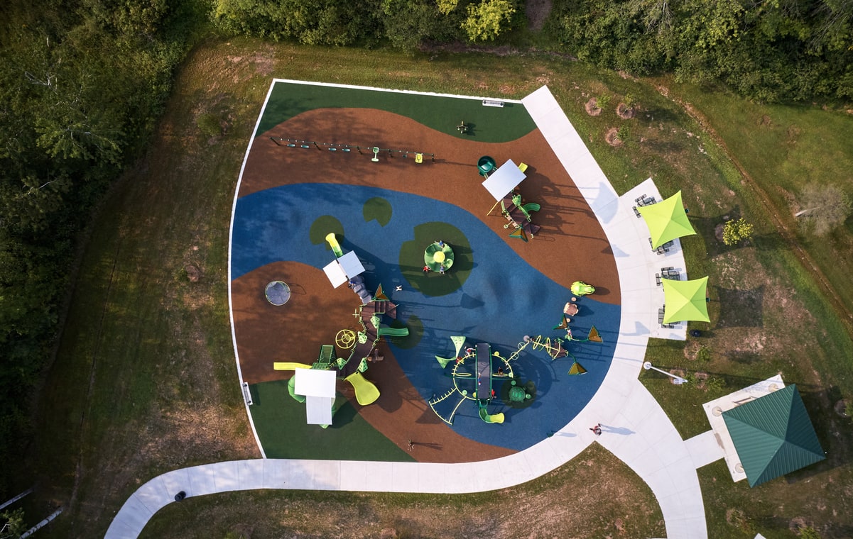 Aerial view of a pond-shaped playground with green equipment, reflecting commercial playground cost for a custom design.
