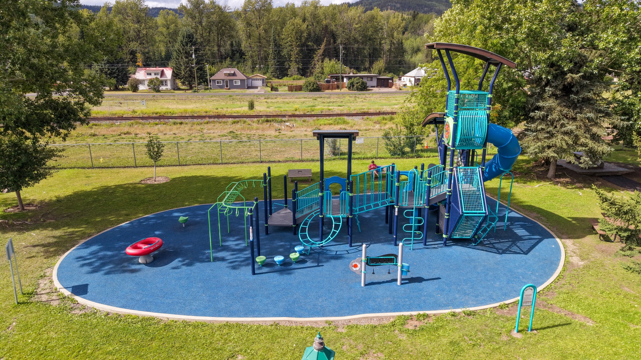 Aerial view of the blue and teal playground at Steelhead Park in Houston, BC, beside the rail line.