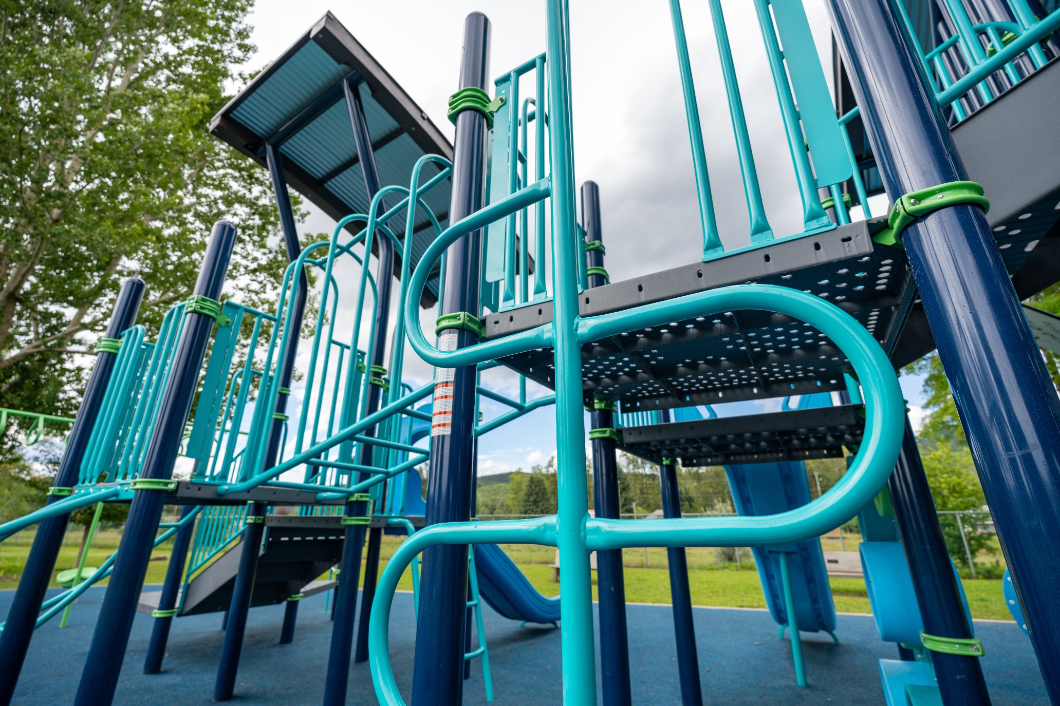 Low angle view of teal railings, metal decks and grab rails on a modern play structure.