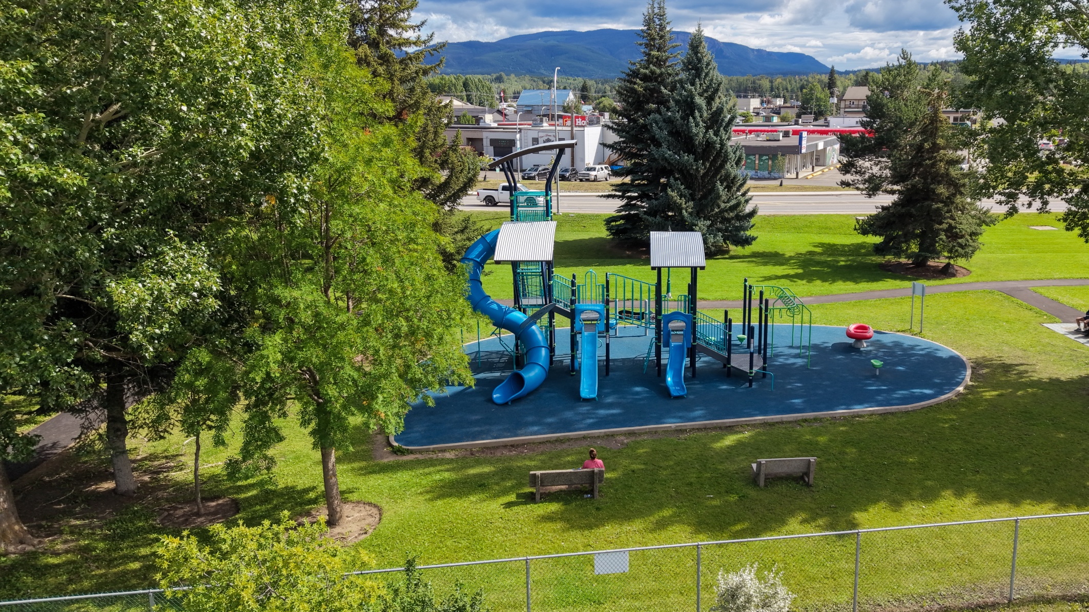 Aerial view of Steelhead Park playground in Houston, BC, with the town and mountains in the background.