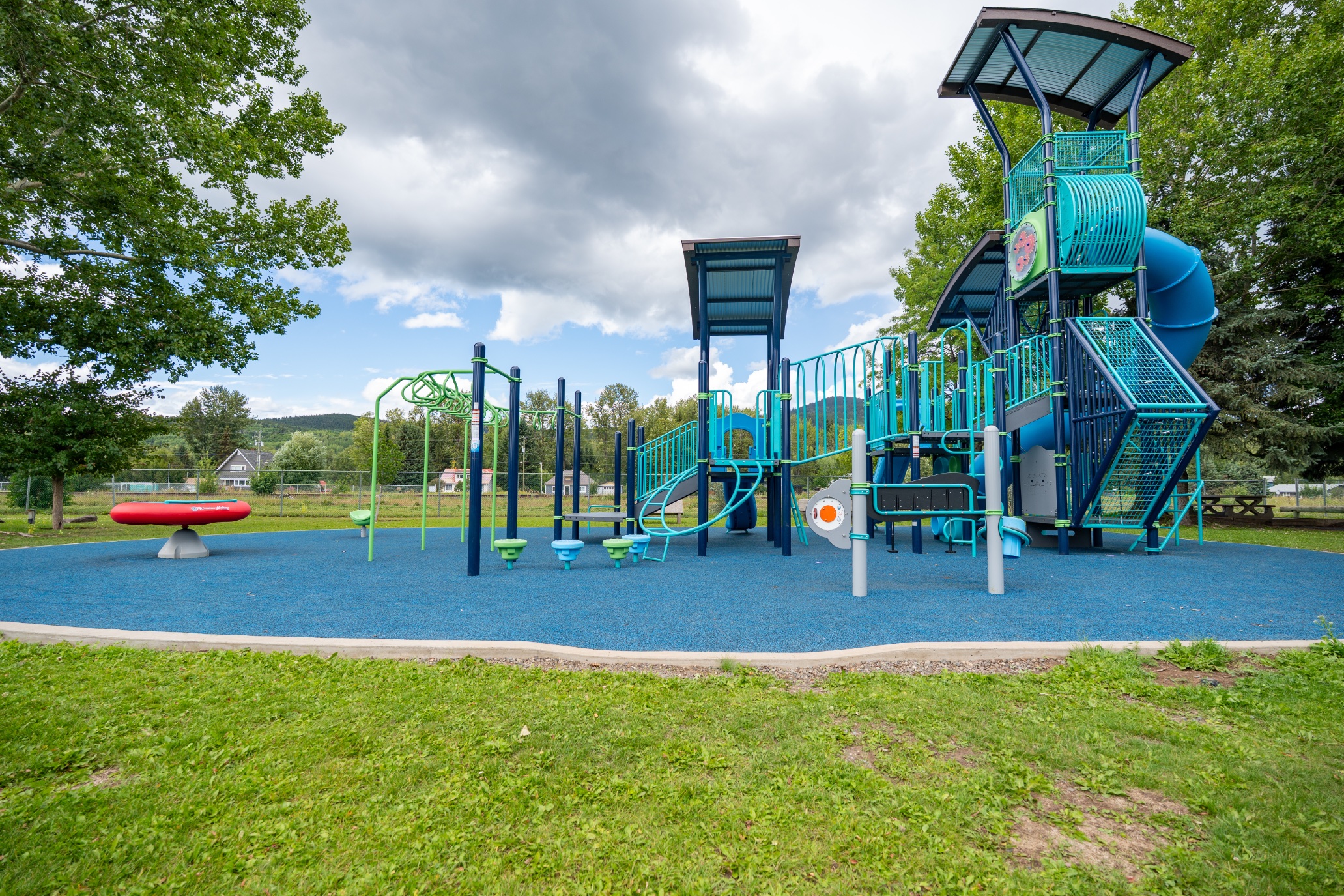 Wide view of the play area at Steelhead Park in Houston, BC, with climbers, spinners and a tall tower.