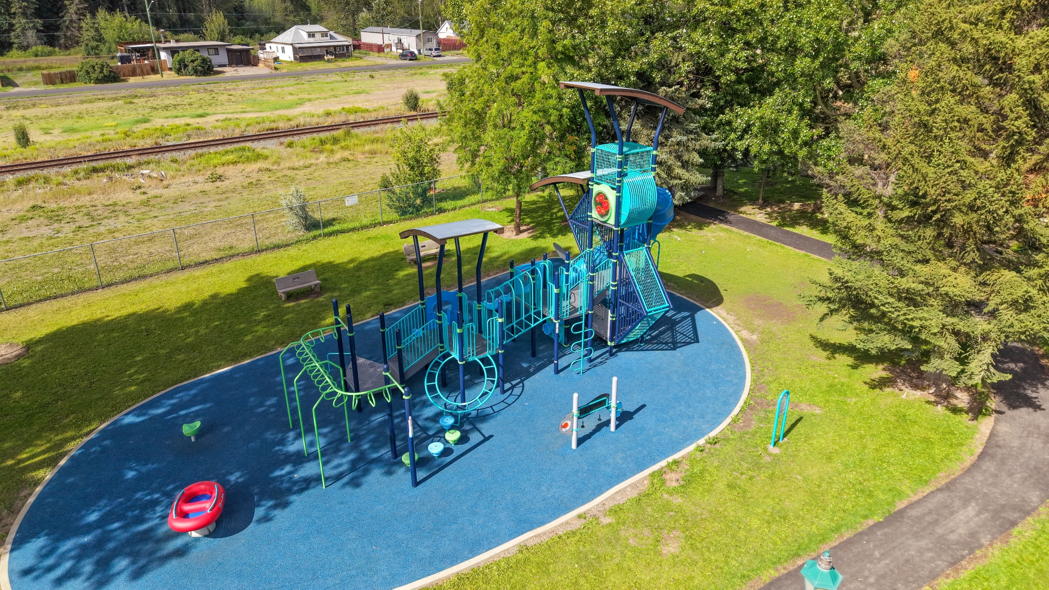 Aerial view of a curved blue play surface with a tall tower, tube slide and green monkey bars.