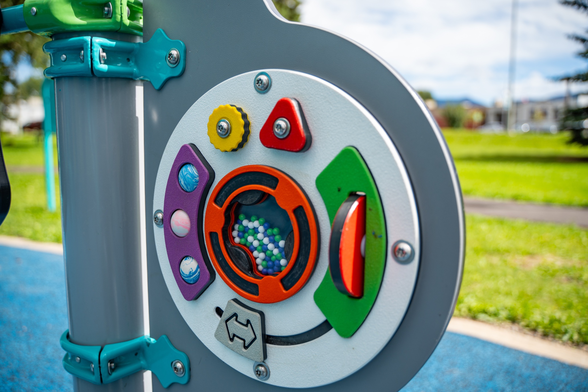 Close-up of a sensory play panel with gears, sliders and a bead window on a grey post.