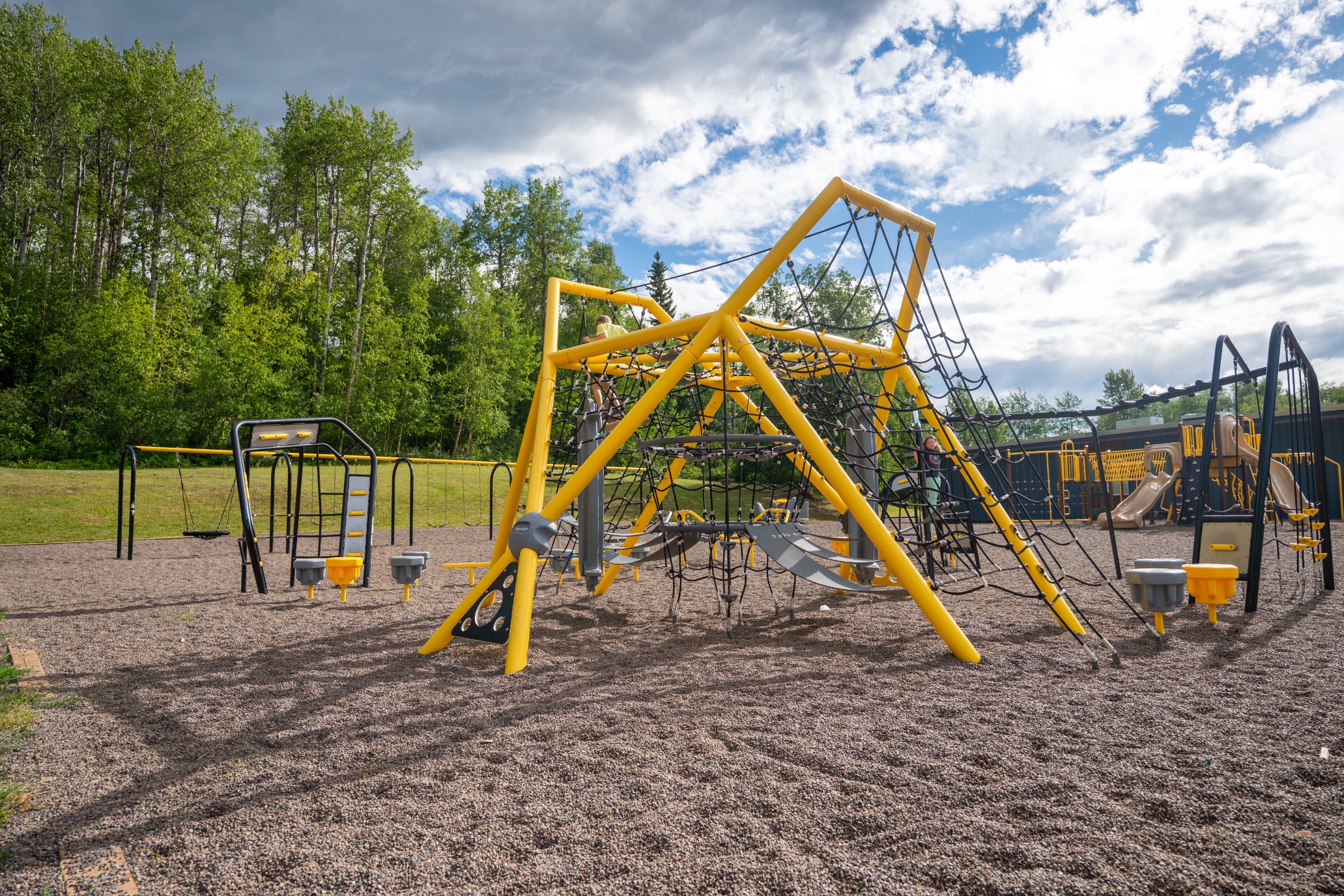 Large rope pyramid climber and swings, a design feature that can influence commercial playground cost.