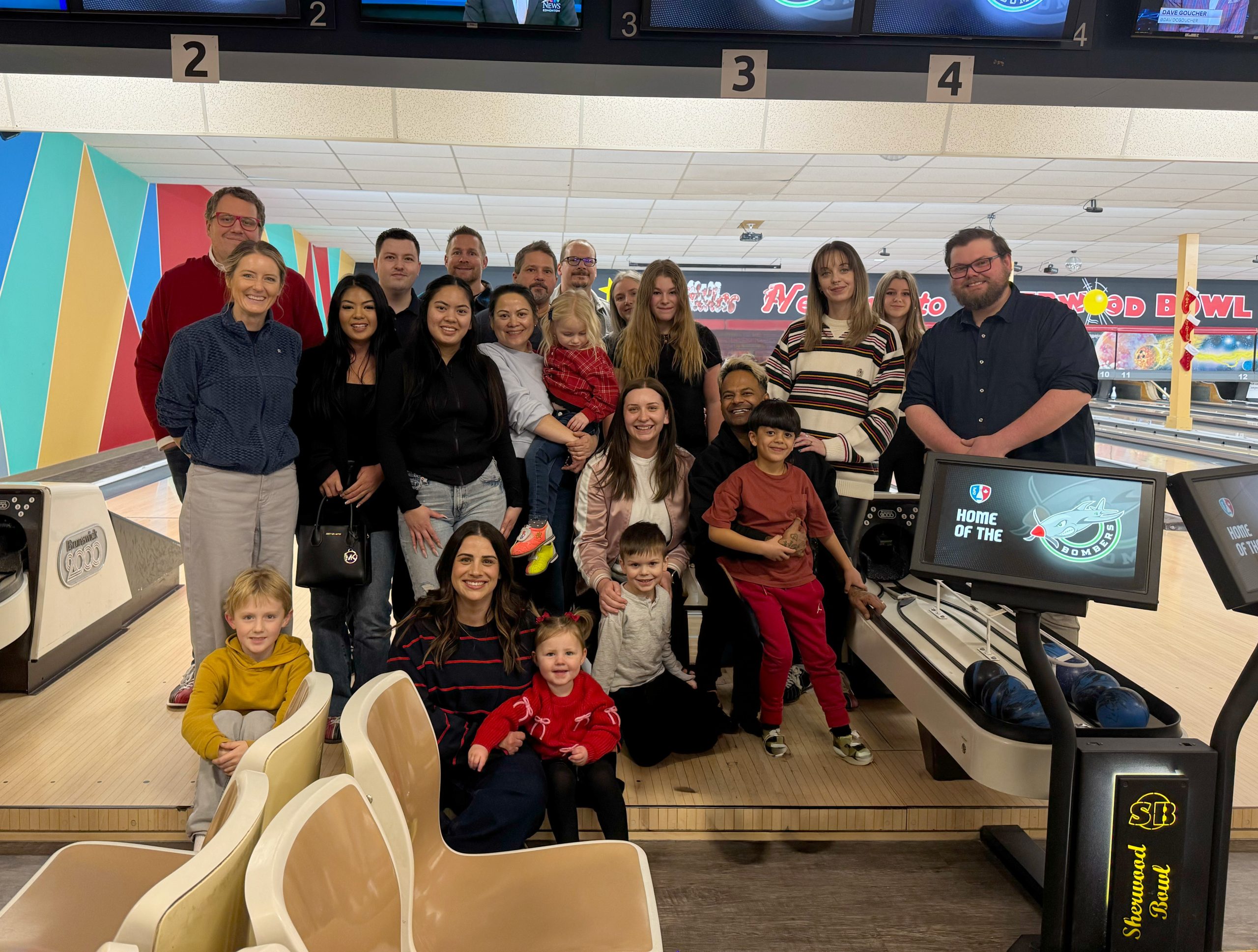 CRS team members and their families gathered for a group photo at a bowling alley during a staff event.