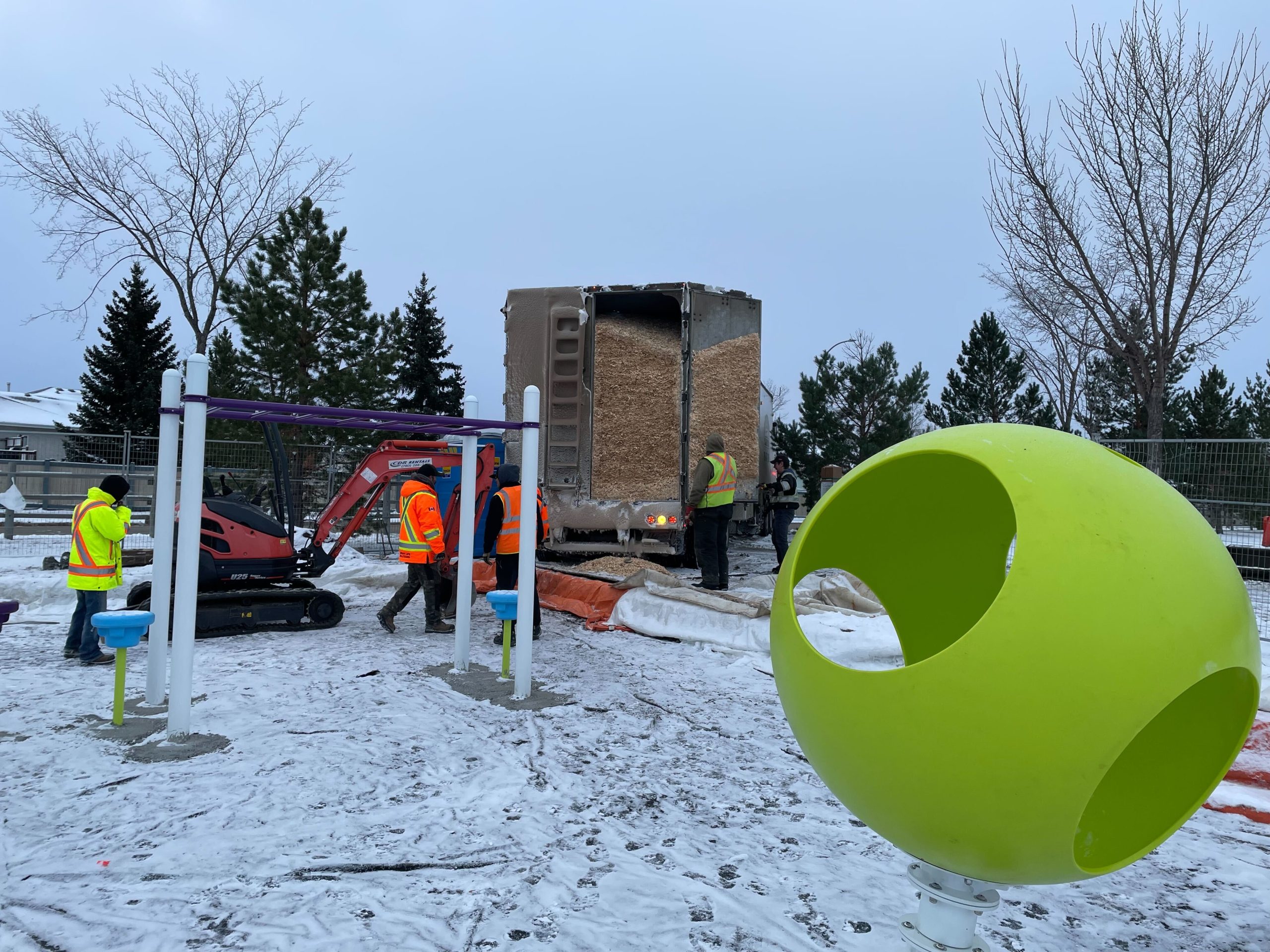 Workers unloading a truckload of wood chip surfacing, a key line item on a playground planning checklist.