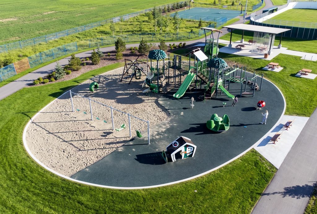Aerial view of an oval playground with sand and rubber zones, a layout rich in commercial playground design ideas.