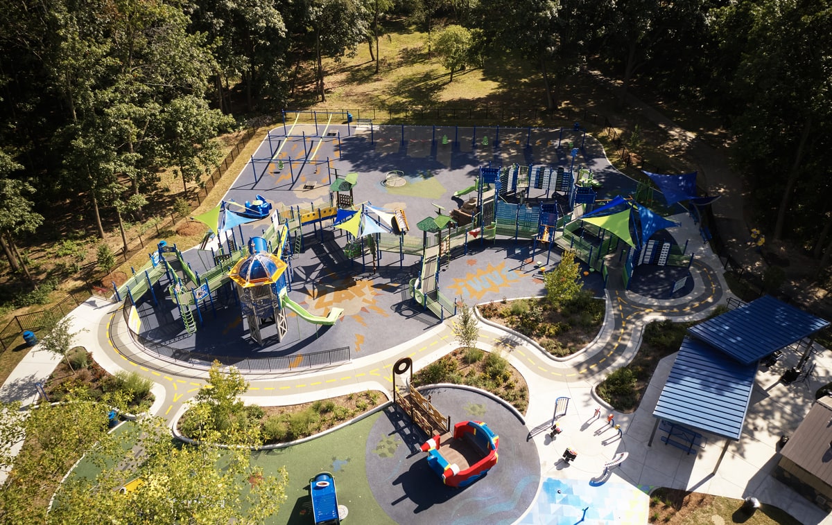 Aerial view of a blue and green playground with a superhero theme, shaped by a solid playground planning checklist.