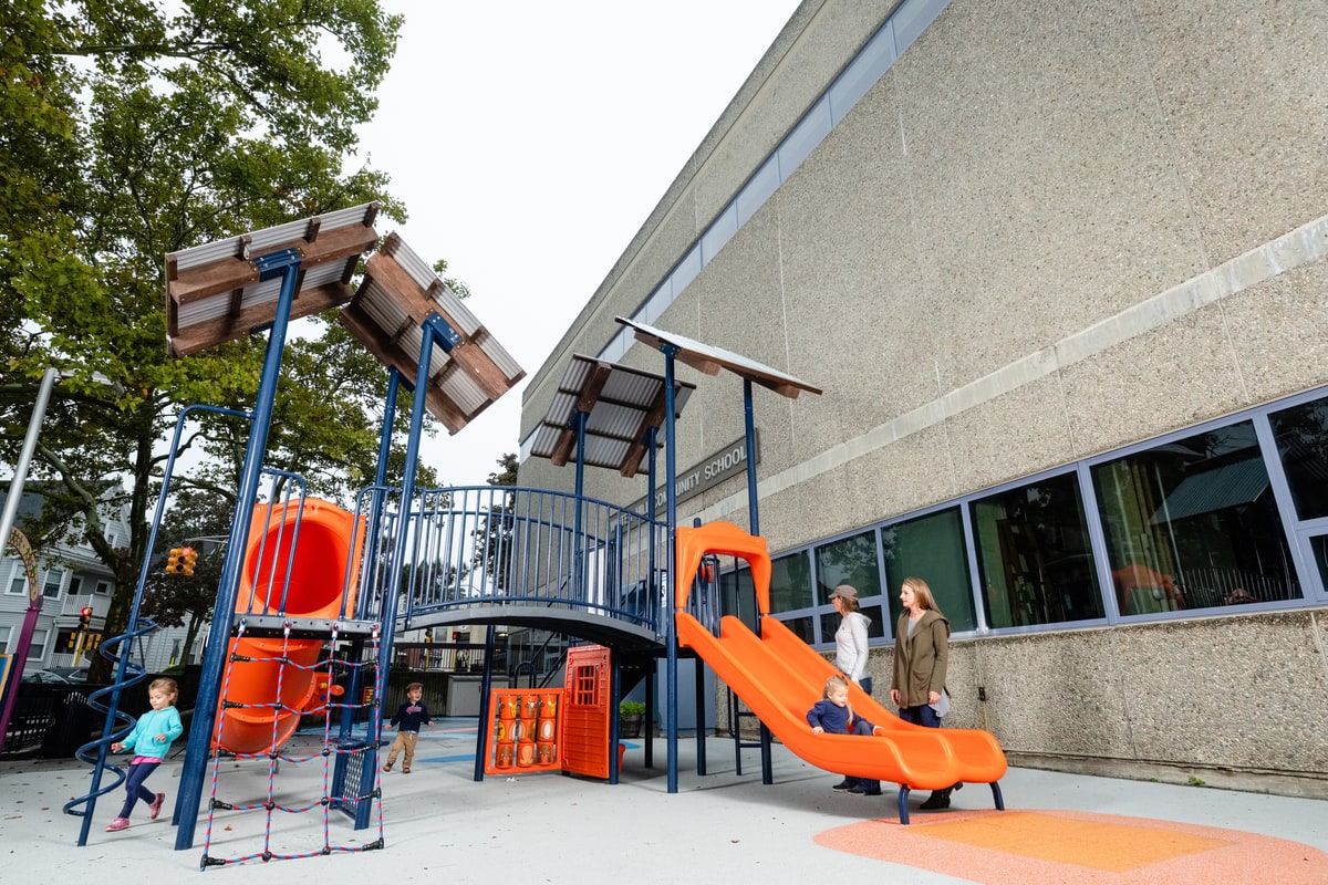 Orange tube slide and tower at a community school playground, the kind of project shaped by how to get a playground grant.