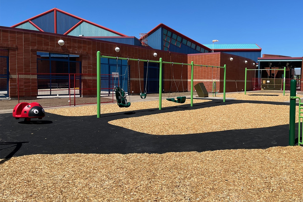 Swing set and ladybug spring rider on a school playground, an upgrade shaped by how to get a playground grant.