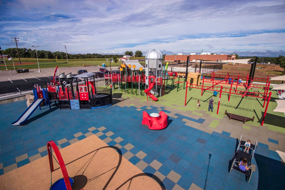 Blue, tan and green rubber tiles, a colourful choice among playground surfacing options, cover the entire play area.