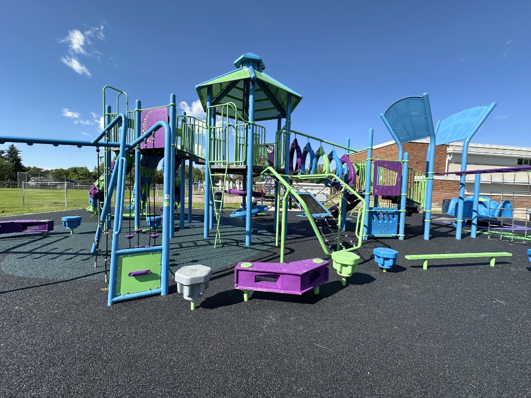 Blue and green play structure with a gazebo roof, stepping pods and a balance beam on black rubber.