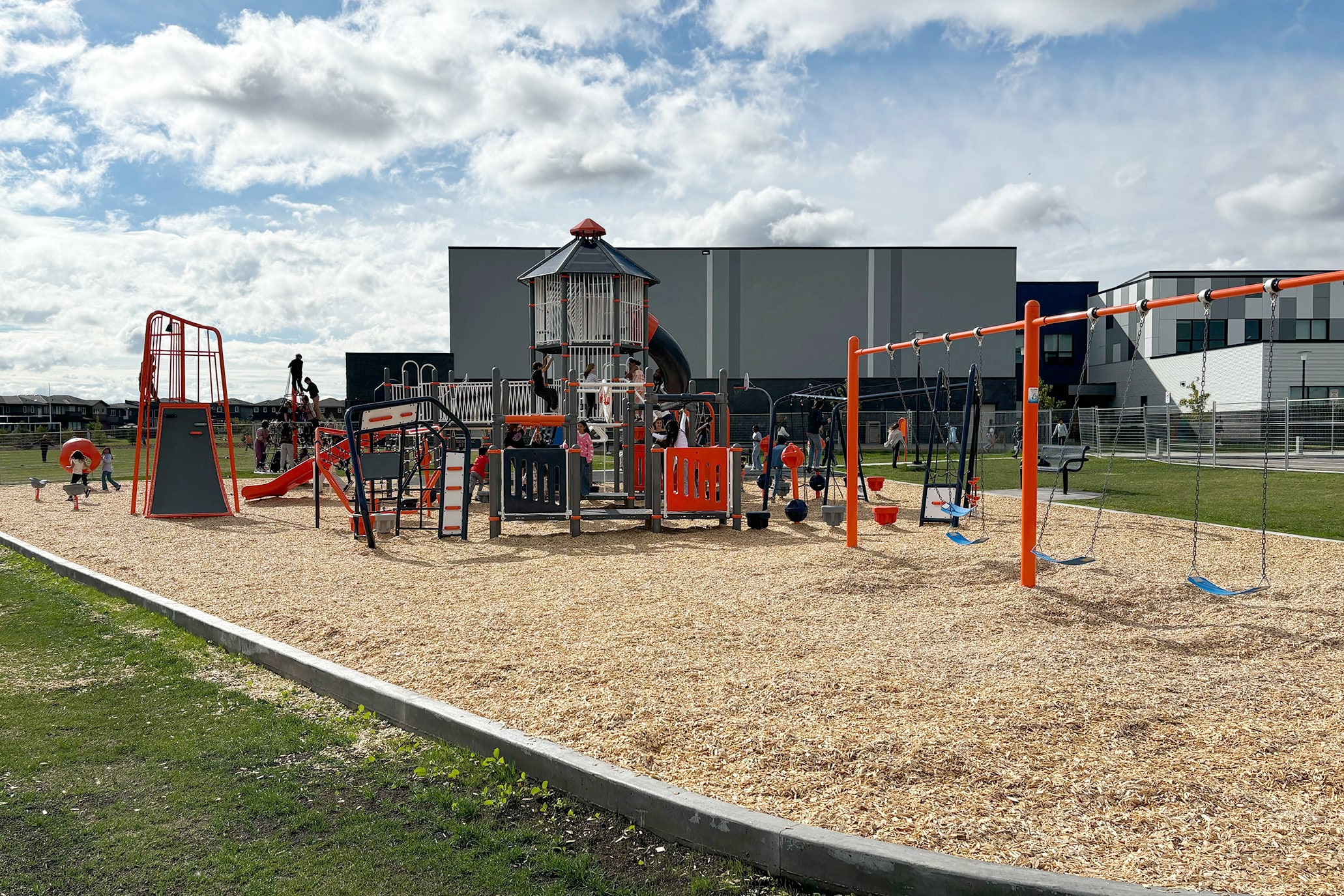 School playground planning placed this orange and blue tower, climbers and swing set beside the school.